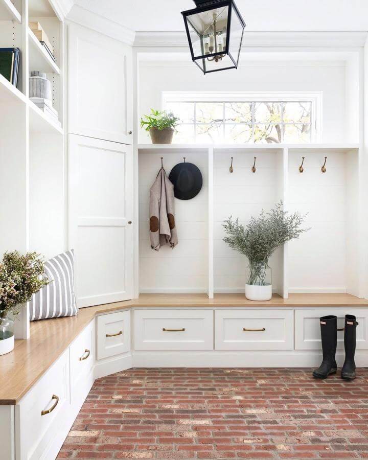 Red brick tiled mudroom flooring ideas from @briahammelinteriors with white built-in storage and natural wood bench seating.