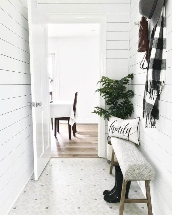 Penny Lane gray hex vinyl flooring in bright mudroom from @uglyducklinghomes with cozy bench and greenery accents.