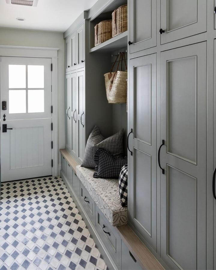 Muted gray and white diamond-pattern tile flooring in mudroom from @mindygayerdesign. Stylish and durable mudroom flooring ideas with cozy built-in bench seating.