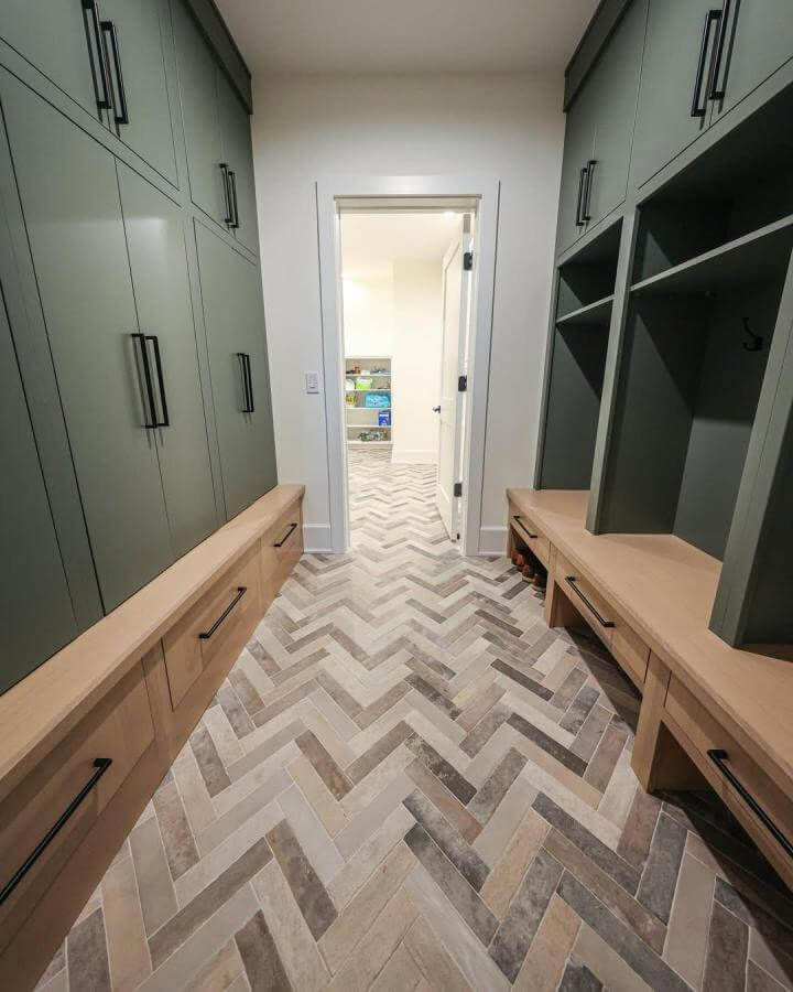 Beige gray herringbone tile flooring in mudroom with wood benches from @standard_tile. Durable and stylish entryway design.