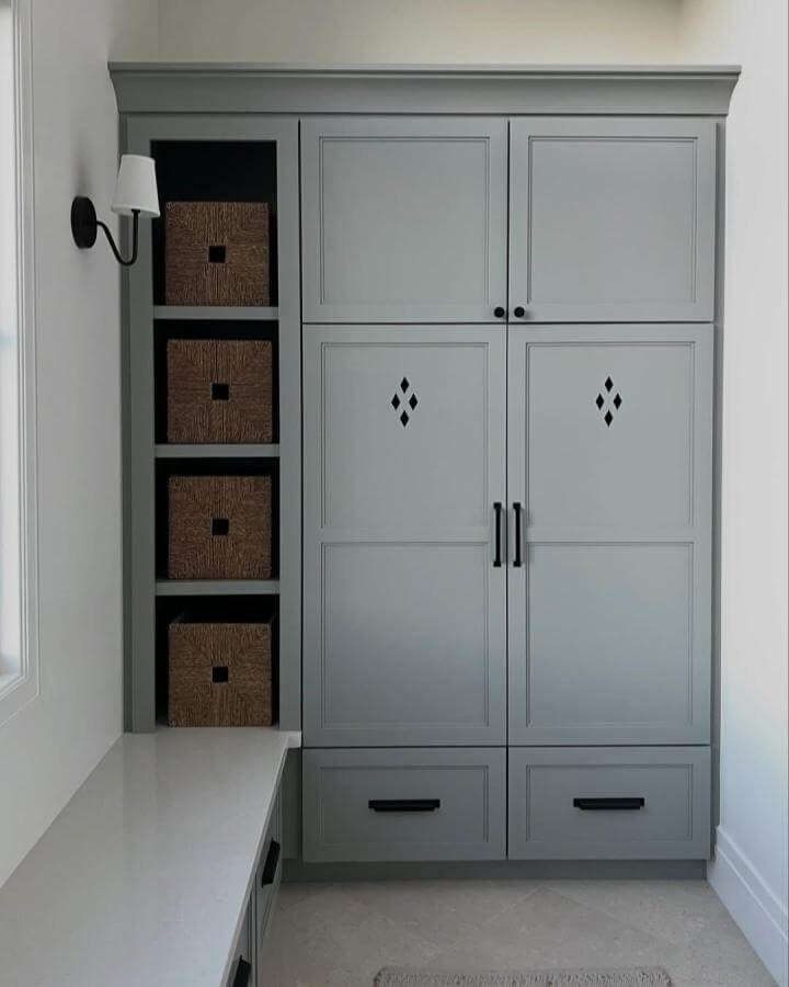 Gray built-in cabinet with black handles and woven baskets for shoe and accessory organization in a mudroom by @curatedbyjose.