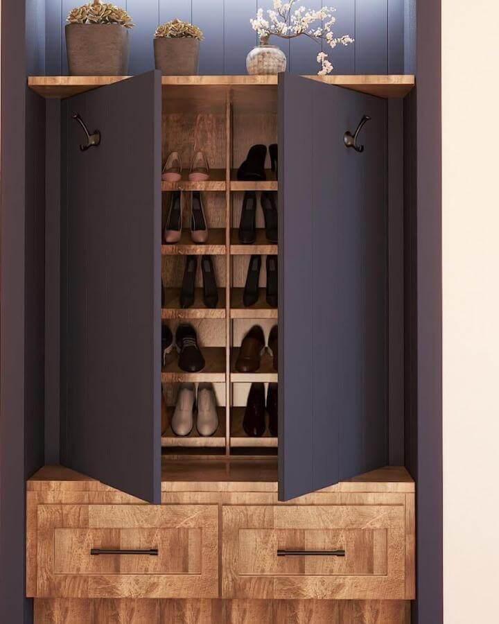 Dark blue and natural wood mudroom cabinet with organized shoe shelves and black metal hooks from @_claudia.newmaker_ for stylish entryway storage