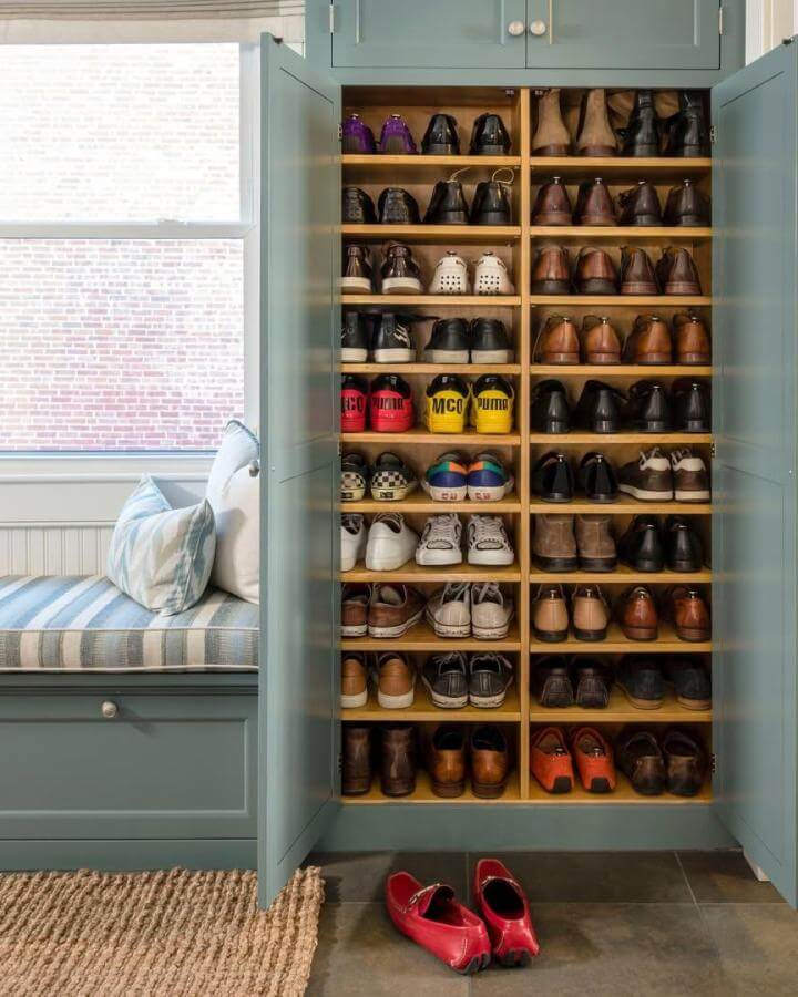 Blue-green wooden built-in shoe cabinet from @sabrinacolequinn with warm wood shelves and adjacent cushioned bench.