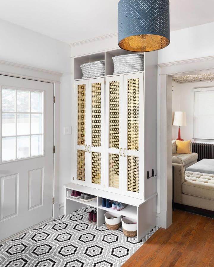 White wood cabinet with woven cane panels and open cubbies in mudroom by @hendricksonphoto. Stylish concealed shoe storage with natural texture accents.