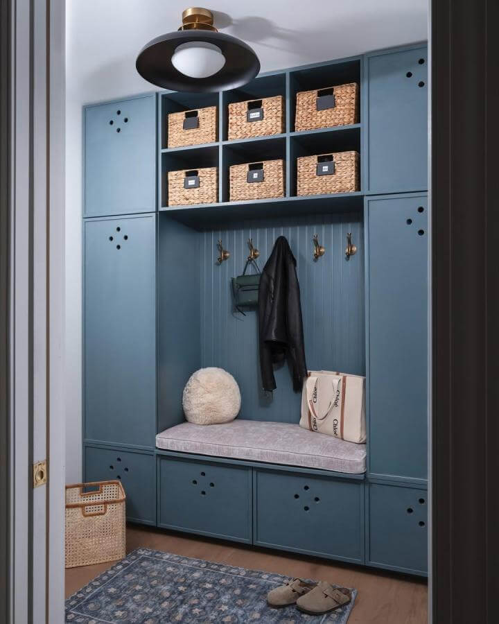 Blue built-in bench with brass hooks and woven baskets mudroom shoe storage ideas by @asloandesign tidy and cozy space.