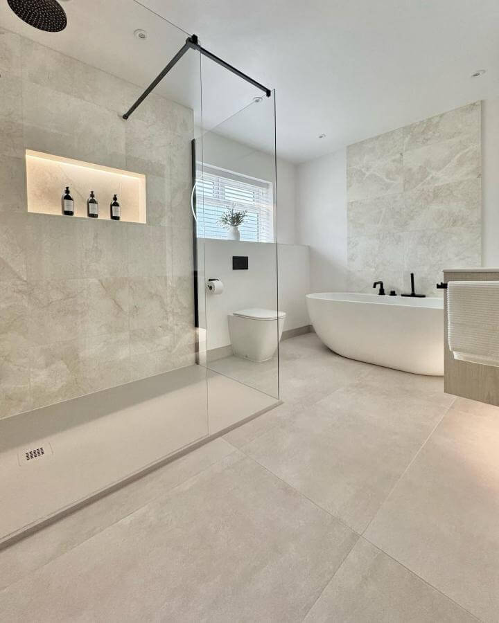 Soft beige natural stone bathroom with minimalist walk-in shower and black fixtures from @thetapend.design. Light and clean atmosphere.