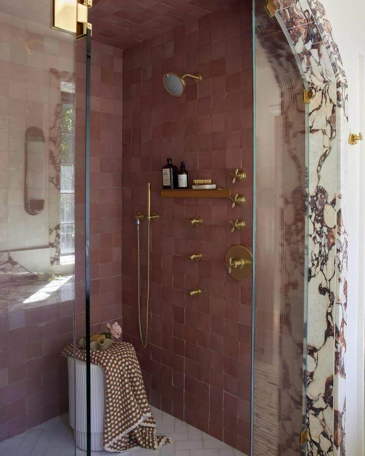 Red vein Calacatta marble archway with pink terracotta shower tiles and brass fixtures from @heathertalbert natural stone bathroom ideas.