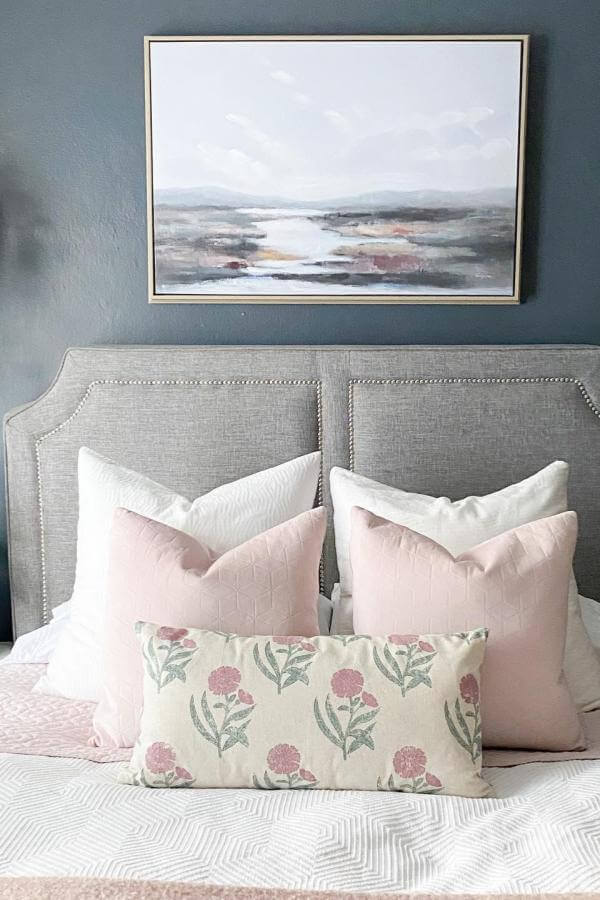 Soft pastels pop against dramatic navy walls in a cozy bedroom from @thesundrenchedbungalow, inspiring navy bedroom ideas.