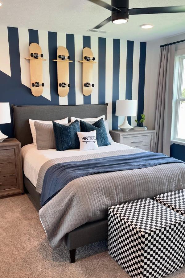 Bold striped walls and skater-inspired art in a modern room from @buildersdesign. Vibrant accents enliven navy bedroom ideas.
