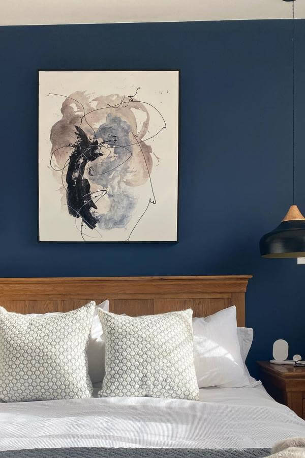 Bold abstract art piece in navy bedroom from @doornumbereleven. Becomes the focal point enhancing room’s depth.