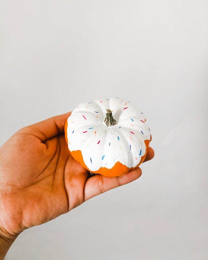 White frosted donut pumpkin from @nathan.et.celine. Colorful sprinkles accent the sweet Halloween craft design.