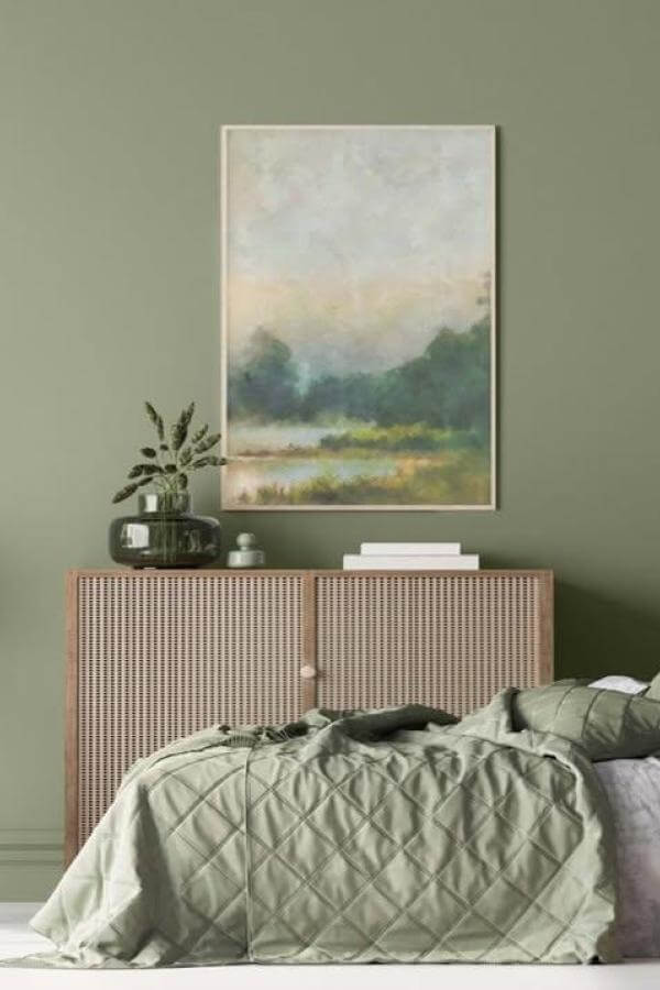 Muted olive green bedroom with tranquil bed and serene landscape artwork from @keim_uk. Calm, natural vibe.
