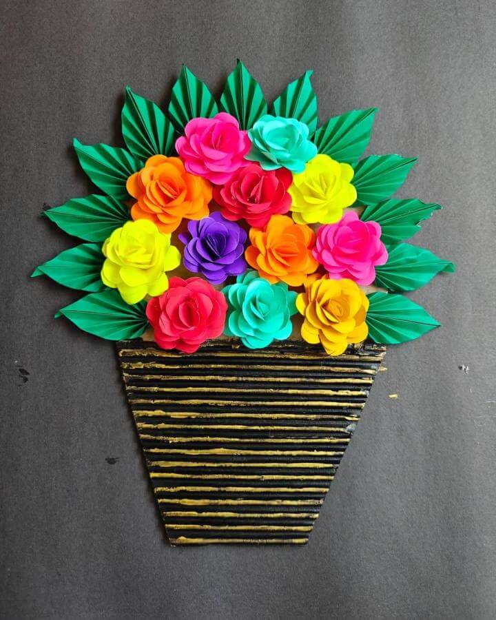 Bright colorful paper flower bouquet with green folded leaves in striped vase from @creativesuu. Vibrant paper crafts for adults.