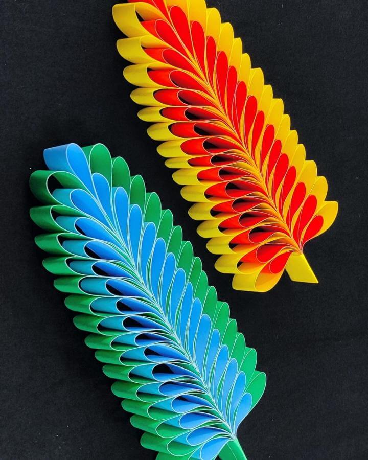Bright layered paper feather craft in yellow, red, green, and blue from DIY And Paper Crafts with intricate folding detail paper crafts for adults.