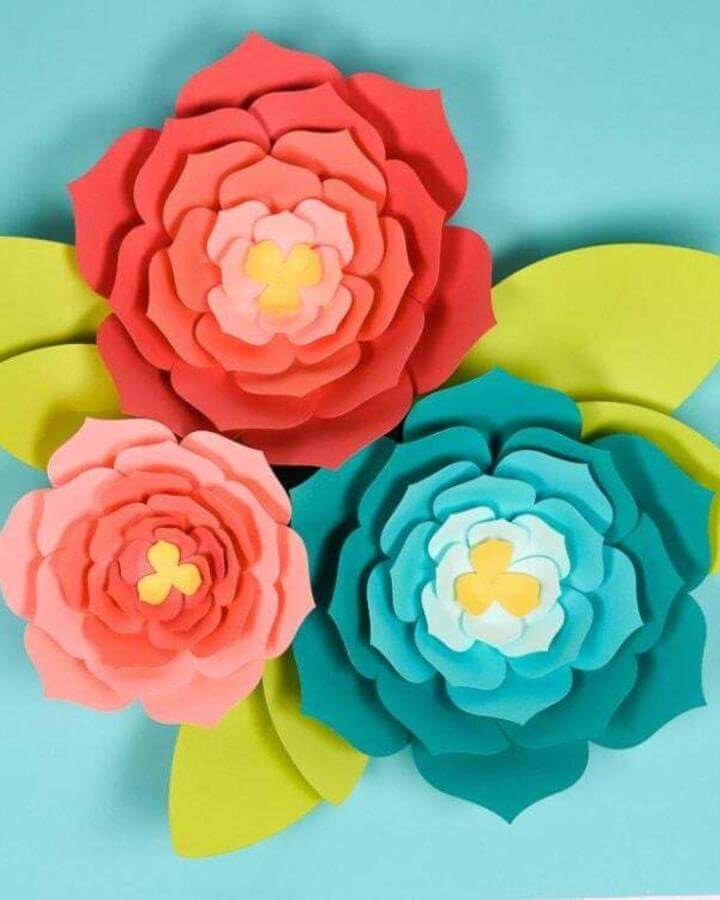 Bright coral, teal, and yellow layered paper flowers with green leaves from Hey Let's Make Stuff for paper crafts for adults wall decor.
