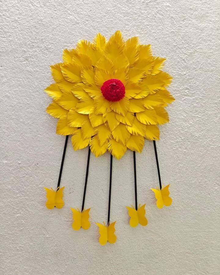 Bright yellow feathered paper flower with red center and dangling yellow butterflies from @creativesuu. Paper crafts for adults wall decoration.
