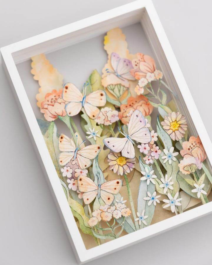 Soft pastel layered butterfly and floral paper craft shadow box from @marinapapercuts delicate hand-cut details paper crafts for adults.