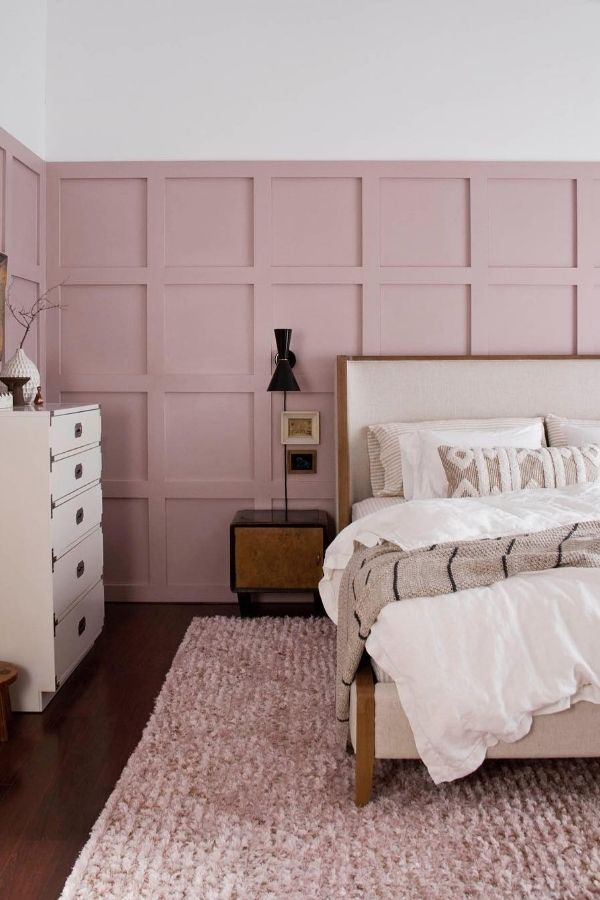 A cozy bedroom featuring soft blush tones and textured decor.