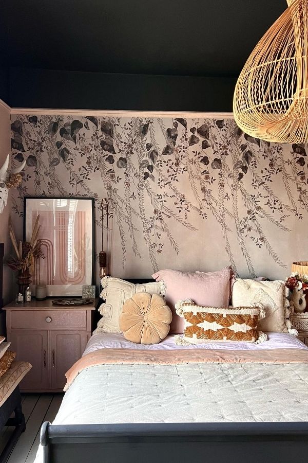 Moody pink bedroom featuring botanical wallpaper, elegant bed, and decorations.