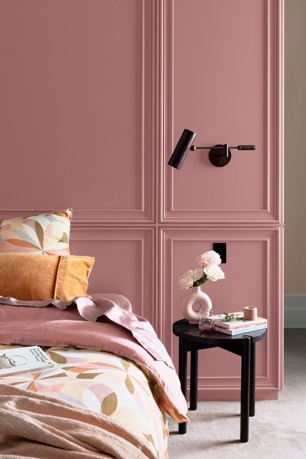 A serene bedroom featuring muted pink tones and modern geometric patterns.