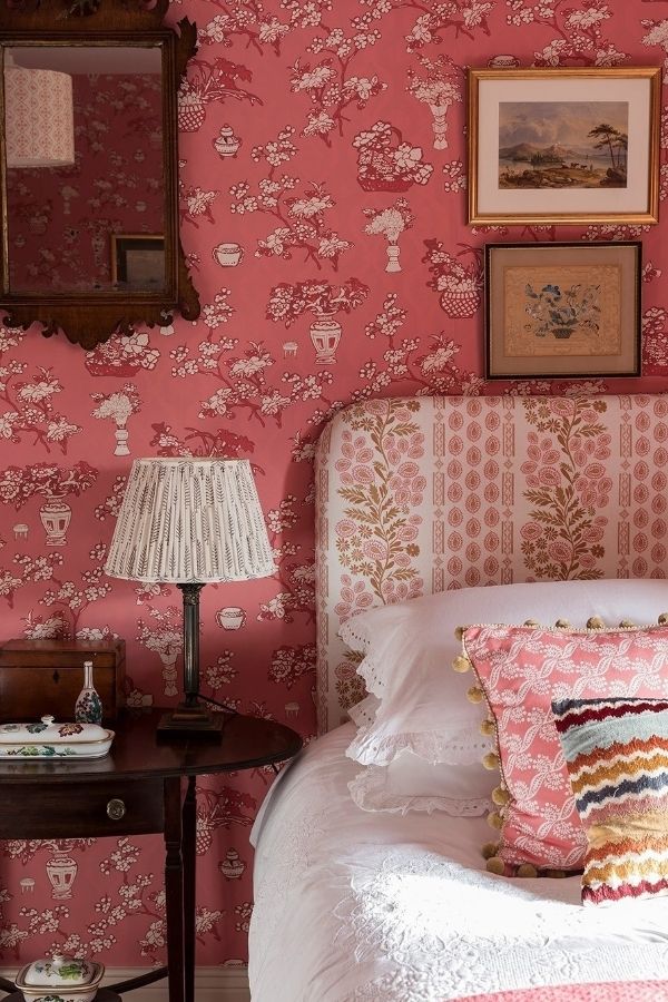 Vintage bedroom featuring floral wallpaper, antique furniture, and soft lighting.