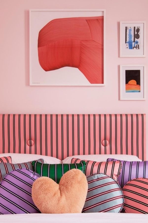 Vibrant pink bedroom, striped curtains, cozy bed, playful décor.