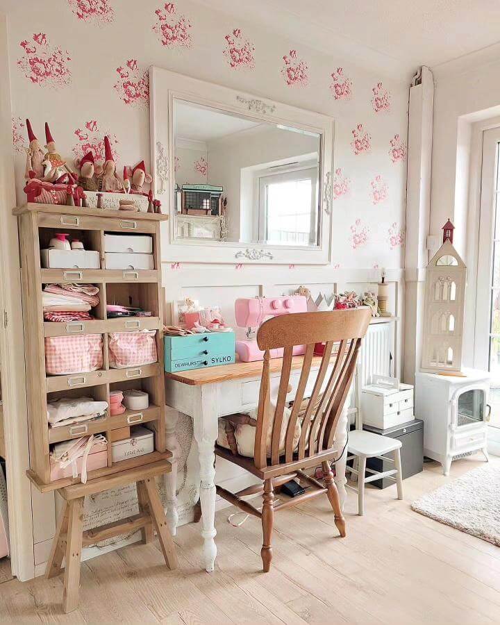 Pink floral wallpapered craft room corner with vintage wood furniture and pastel pink sewing machine from @pink_life_interiors, cozy and organized workspace.