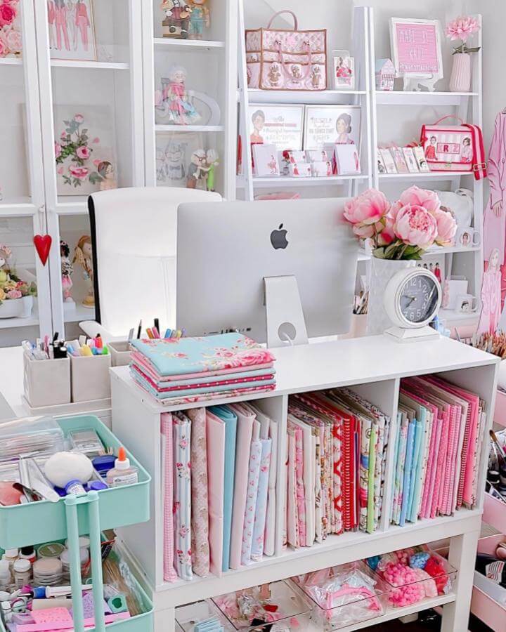 Soft pastel pink craft room with floral fabrics and white shelving from @dani_leigh_cosplay. Organized and cozy creative workspace.