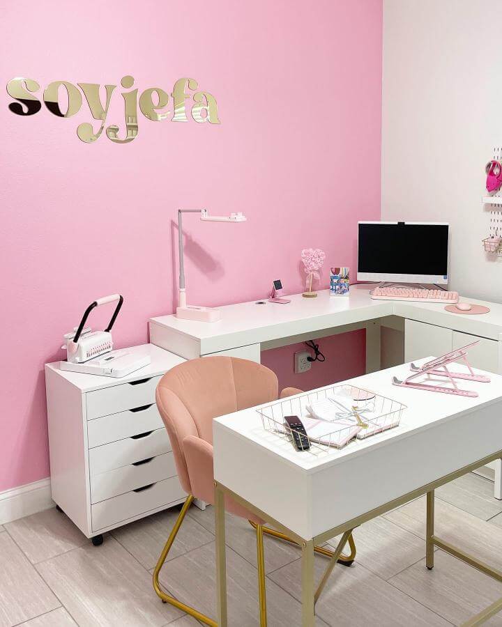 Pink craft room ideas featuring a soft pink wall, white desks with gold accents, and a blush velvet chair by @rosie.and.ava, stylish and organized workspace.