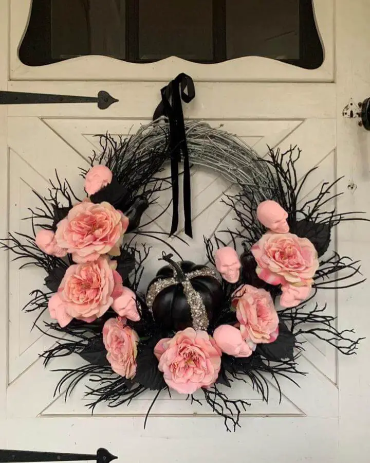 Coral pink roses and black branches wreath from @houseoffigs_. Sparkly pumpkin centerpiece hangs elegantly.