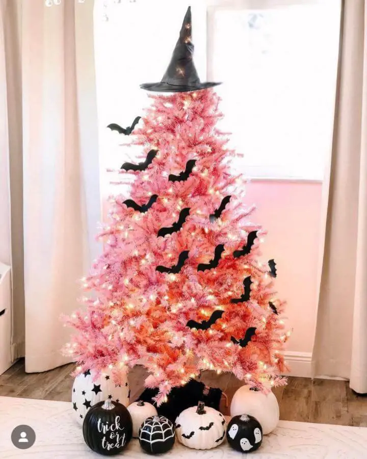 Pink artificial Christmas tree from @celebrationstylist. Black witch hat tops tree with paper bats and Halloween pumpkins below.