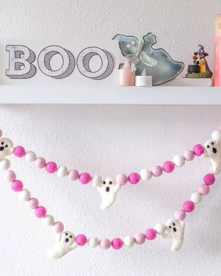 Pink and white felt ball garland with white ghosts from @realms.of.color showcasing pink halloween decor ideas.