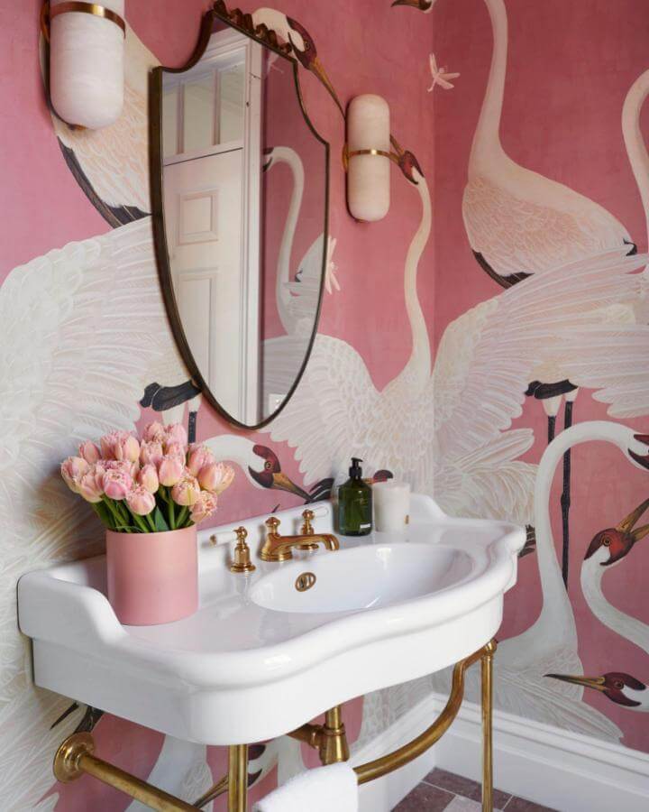 pink powder room ideas featuring brass fixtures and a crane wallpaper from @laurentaylorcreative. Elegant vintage-inspired sink and delicate floral accents.