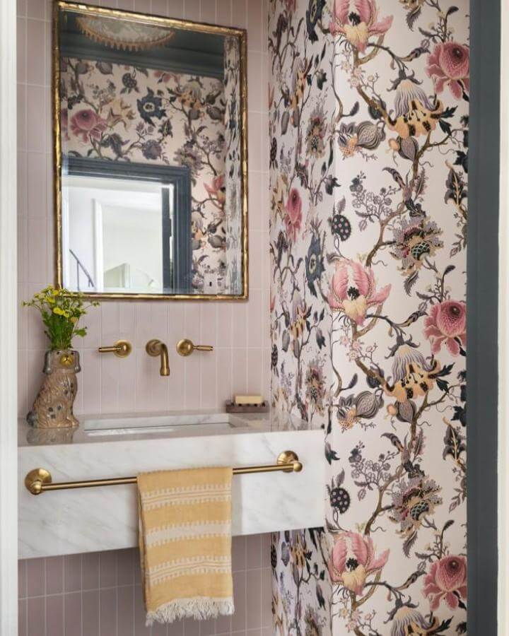 Floral wallpaper and blush tile pink powder room ideas with marble sink and gold fixtures from @miscellanycasa. Chic and lively design.