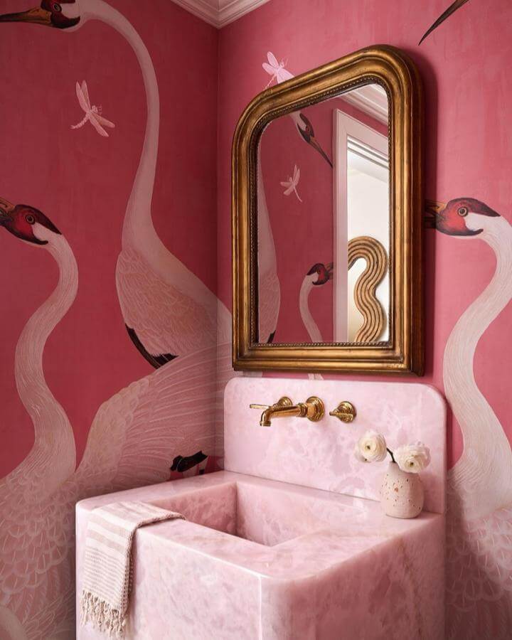 Pink marble sink and pink flamingo wallpaper in powder room from @marblemooninteriors. Vintage gold mirror complements pink powder room ideas.