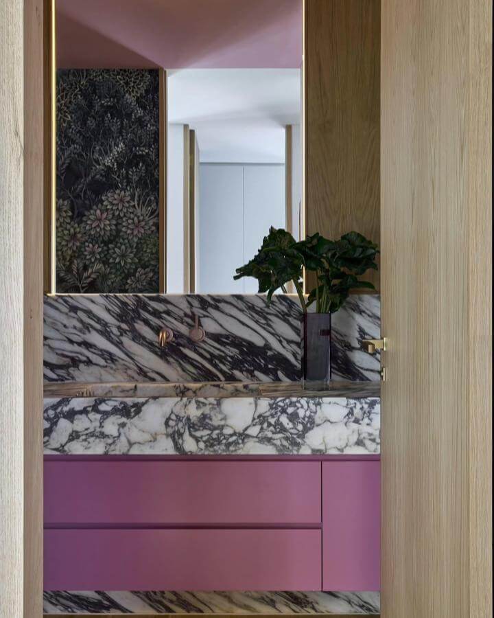 Pink matte vanity with black and white marble countertop in a powder room from @onefour_interiors. Luxurious and bold pink powder room ideas.