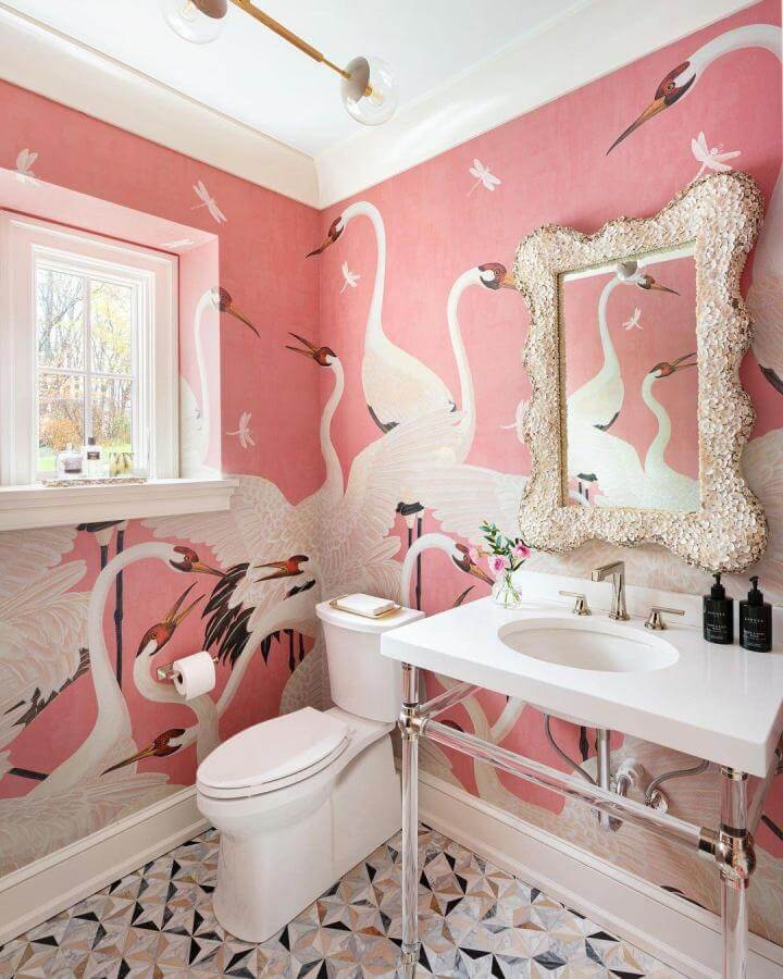 Pink powder room ideas with graceful crane wallpaper from @emptynestersfeathertheirnest. Elegant birds and textured mirror create stylish warmth.