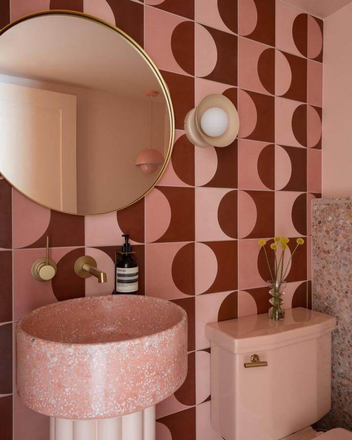 Pink terrazzo sink and geometric tile wall in warm shades enhance pink powder room ideas by @ruemagazine. Chic and modern decor.