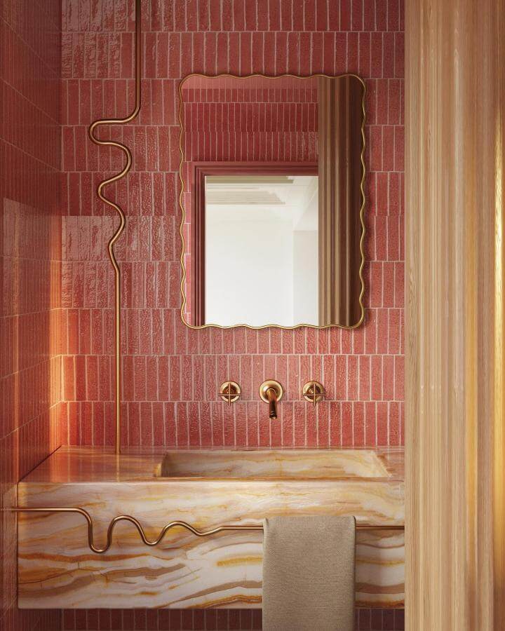 Pink brick tile powder room with wavy gold fixtures and onyx countertop from @susannathomasandco pink powder room ideas with elegant textures and warm tones