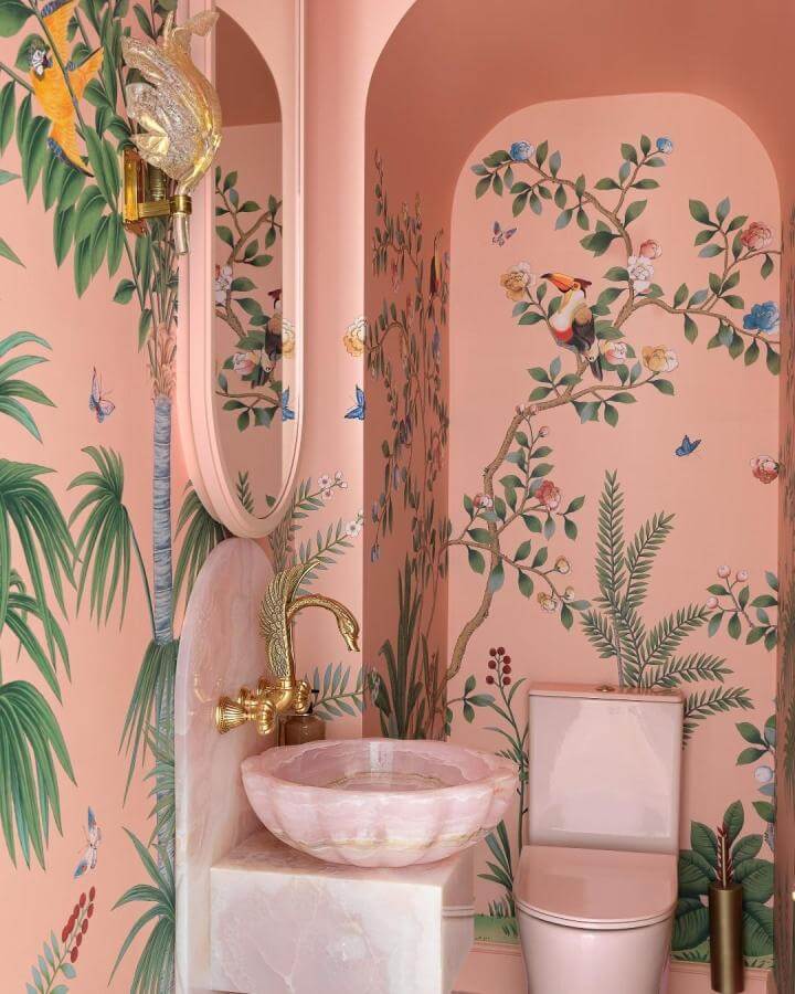 Pink powder room ideas with botanical wallpaper, pink marble sink, and gold swan faucet from @gregnatale creating vibrant elegance.