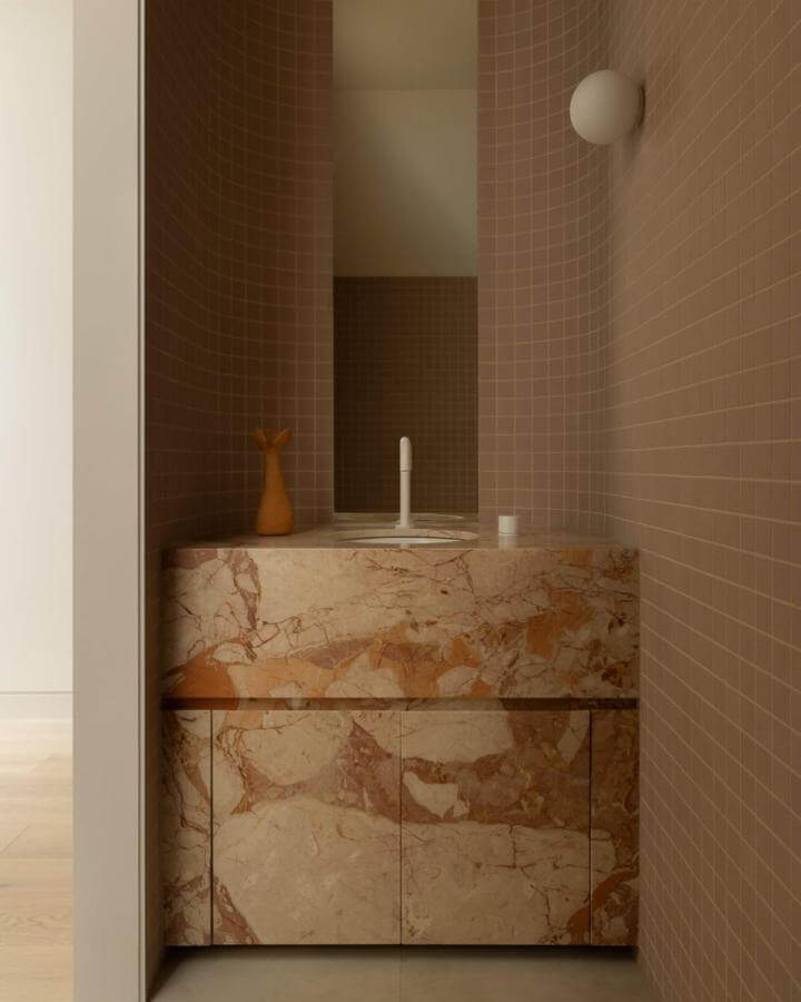 Pinkish beige tiled walls and a rich marble vanity create chic pink powder room ideas by @foxtrot_home with natural stone textures and clean design.