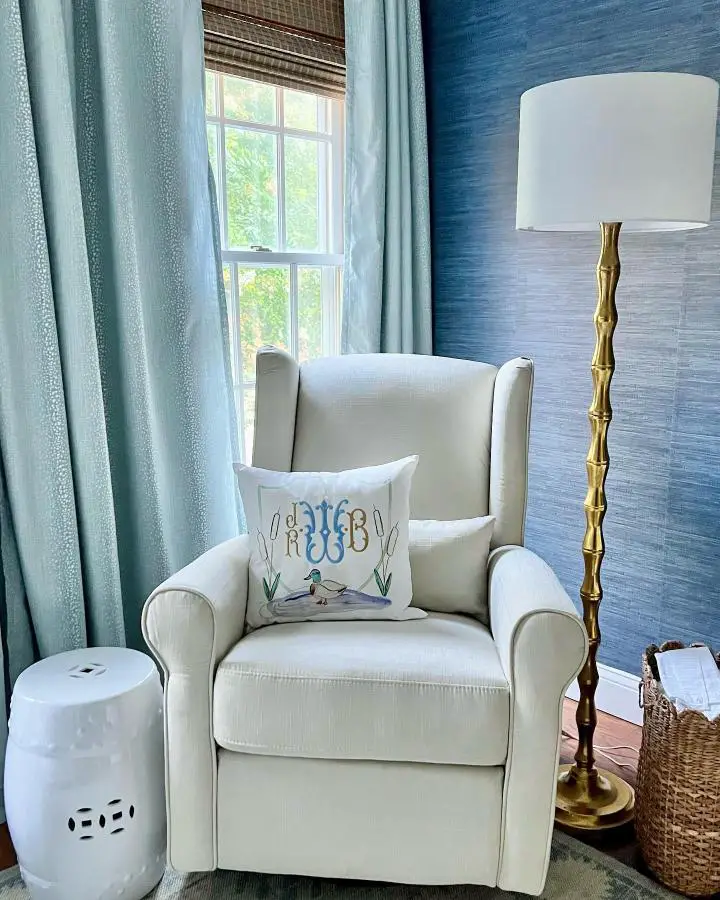 Blue grasscloth wallpaper reading corner from @preppygoods. White wingback chair with monogrammed pillow creates classic preppy style.