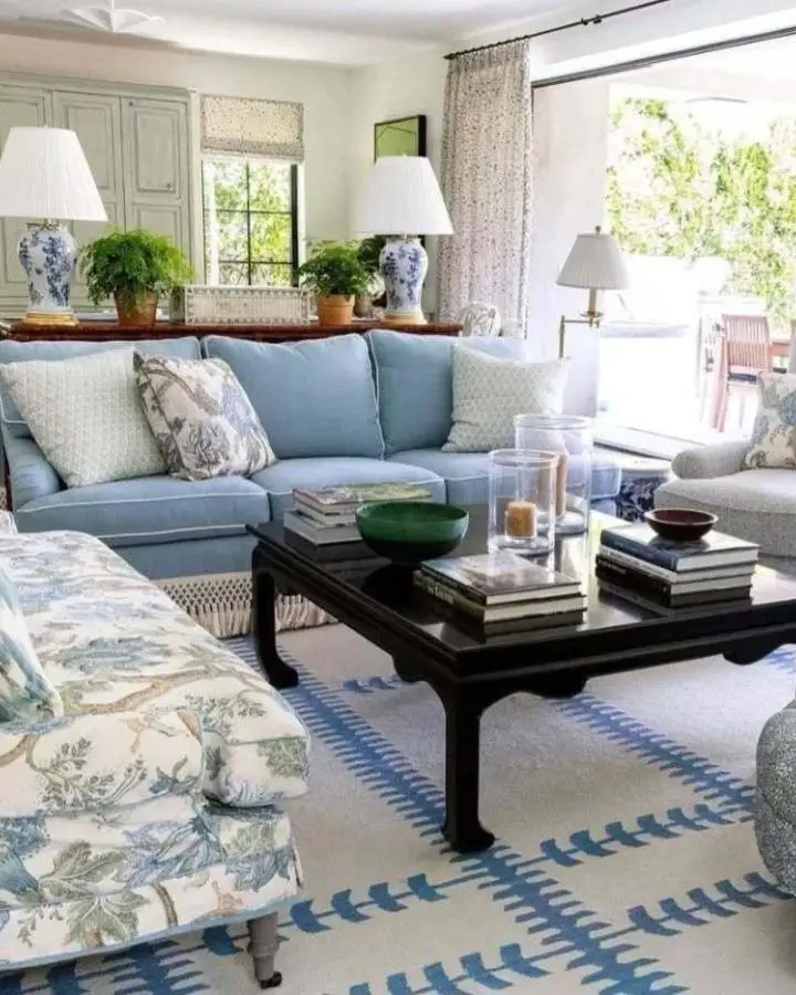Blue sectional sofa with white and blue ceramic lamps from @harlequinhall. Classic coastal living room design.