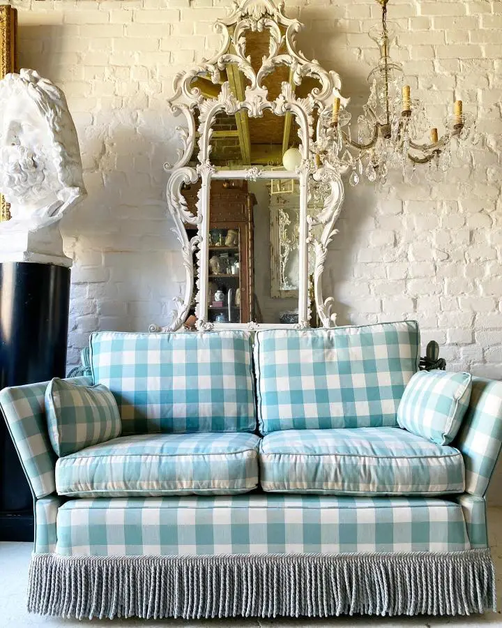 Turquoise gingham upholstered sofa from @relic_interiors showcasing timeless preppy living room ideas against white brick walls.