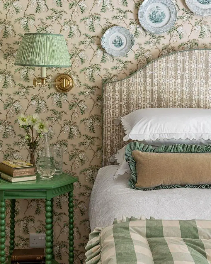 Sage green botanical wallpaper bedroom from @elizabethhaydesign. Coordinating striped bedding and pleated lampshade complete the cottage style look.