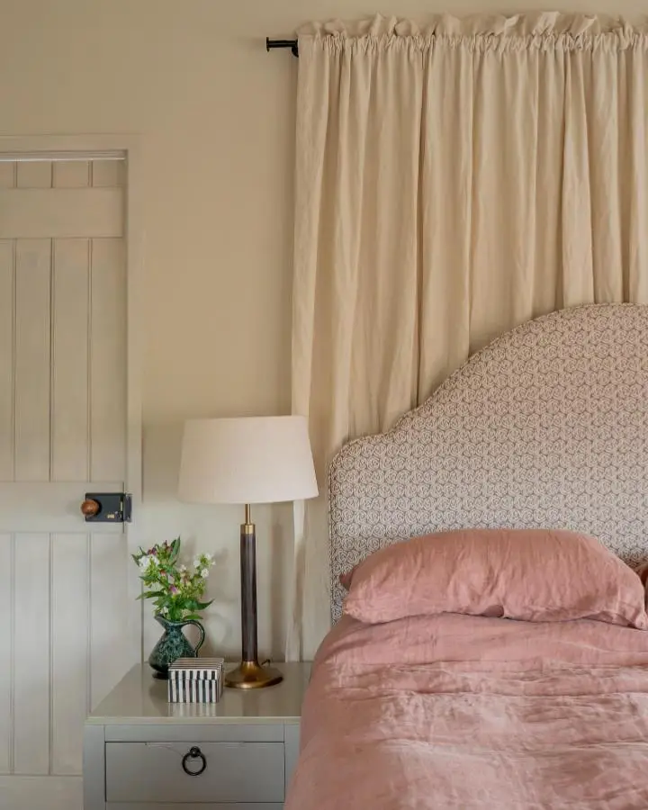 Dusty pink linen bedding from @torimurphytextiles with cream curtains and geometric headboard.