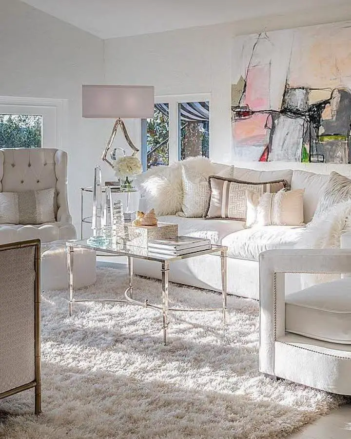 White sectional sofa with glass coffee table from @goedekers. Modern neutral living space with chrome accents.