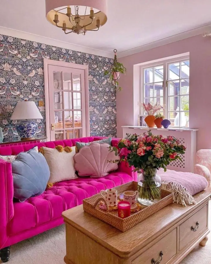 Bright fuchsia velvet sofa with floral wallpaper showcasing pretty living room ideas from @waxpoeticclothing. Traditional meets bold contemporary design.