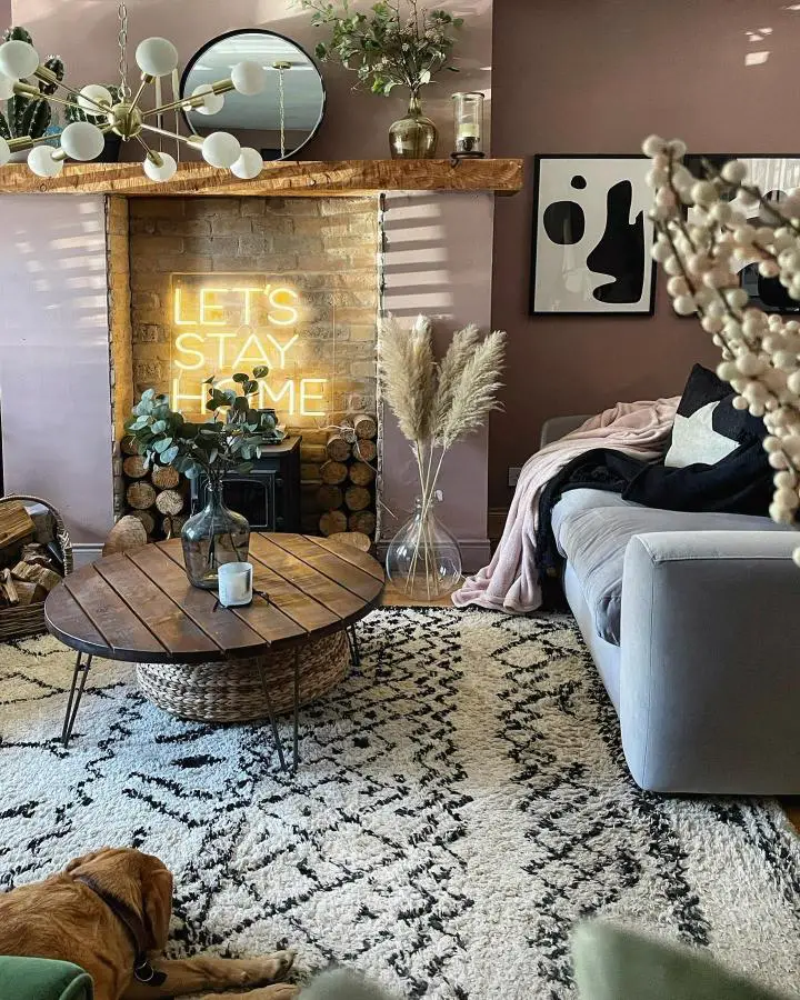 Cozy fireplace with yellow neon sign from @mydarkhome_. Modern rustic living space with wood mantel and brick details.