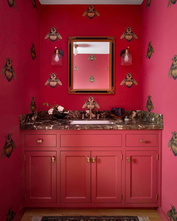 red cabinetry and whimsical bee wallpaper in a red powder room ideas setting by @vickisimondesigner bright and inviting space with marble counter and brass accents